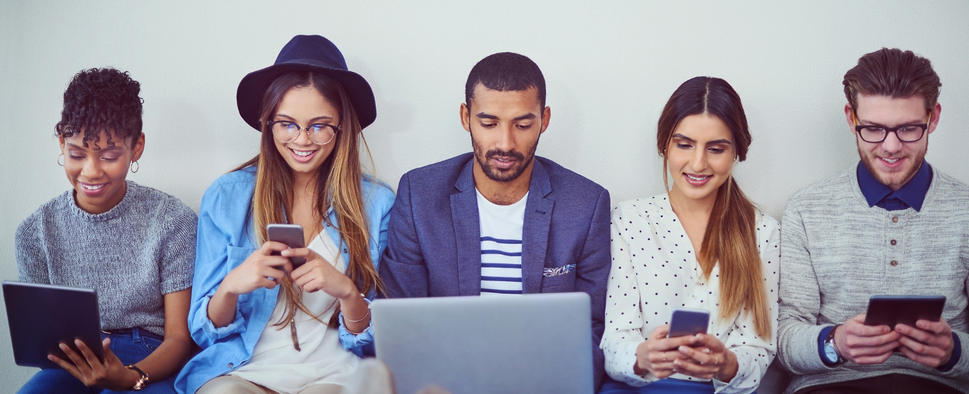 Group of people using phones, tablets, and laptops.